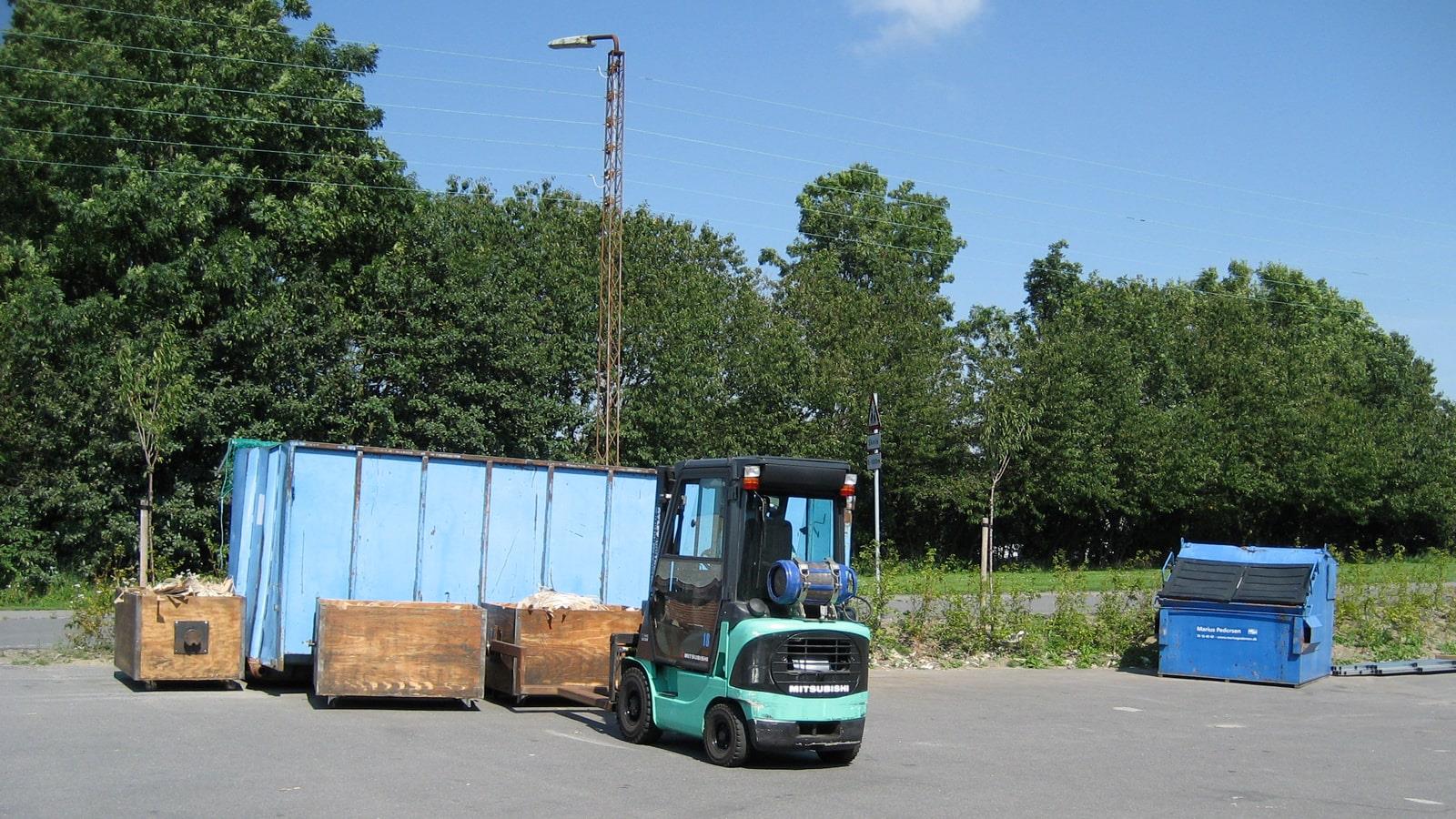 Fork lift truk picks up wooden box with cut cardboard