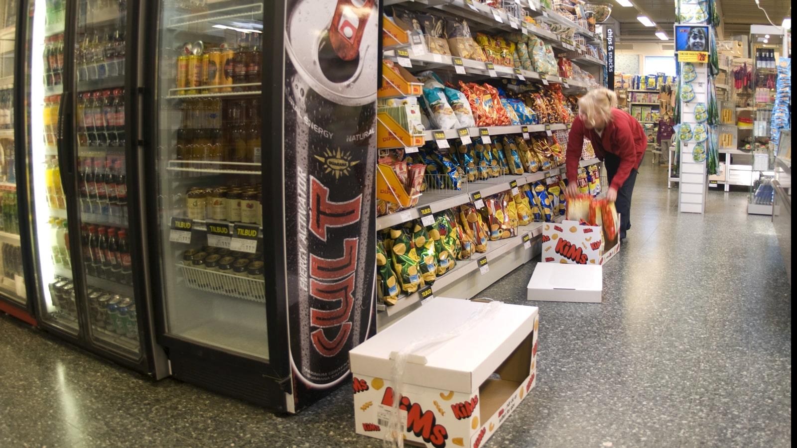 Female employee puts crisps on shelves in SuperBrugsen