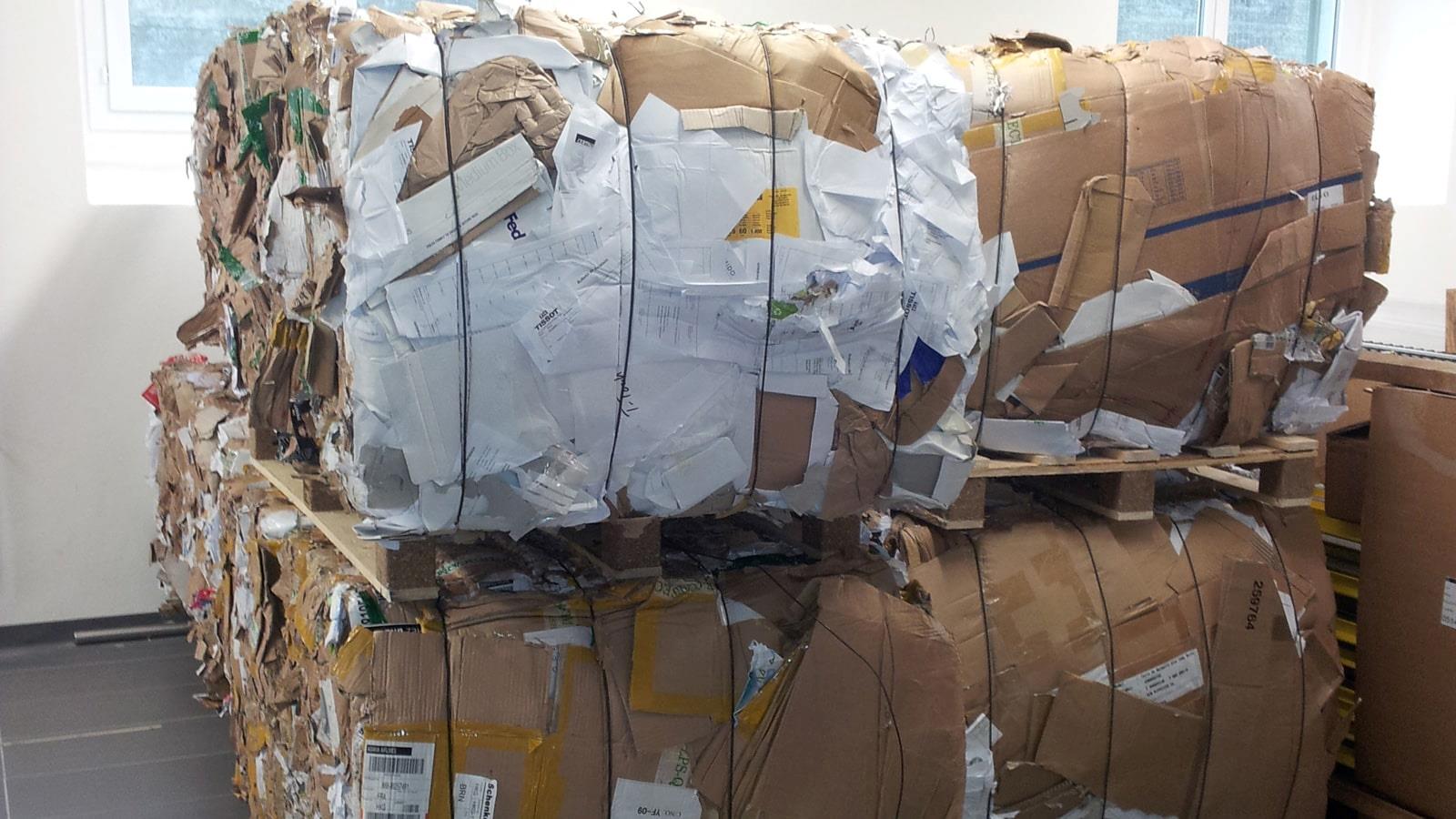 Compressed cardboard bales tied with steel wires stacked in Tissot warehouse